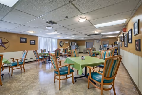 Communal dining room with tables covered in green tablecloths and striped upholstered chairs.