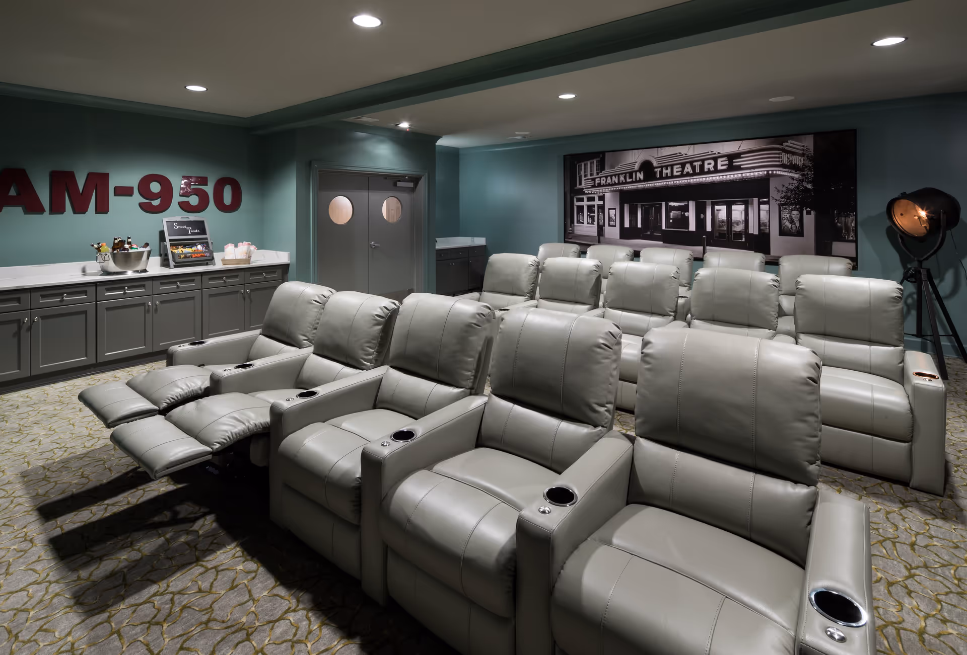 A private theater room with multiple gray leather reclining seats, a concession counter, and a large black-and-white 'Franklin Theatre' photo on the wall.