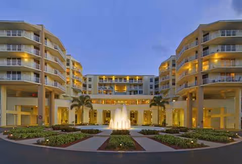 Exterior view of Park Summit with a central fountain courtyard and palm trees.