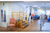 A senior living rehabilitation gym interior with stairs, therapy equipment, mats, and exercise balls.