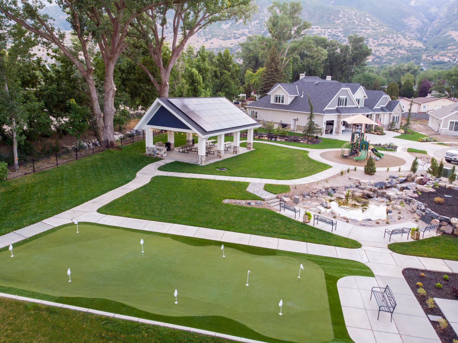 Aerial view of the Covington Senior Living grounds with a putting green, covered pavilion, walking paths, playground, pond and residence buildings.