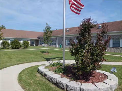 Exterior view of Forsyth Care Center with a flagpole, circular planter, and walkway.