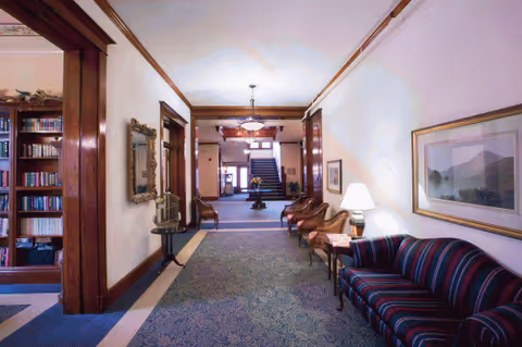 A long hallway in Rathbone Home with seating along walls and a bookshelf.