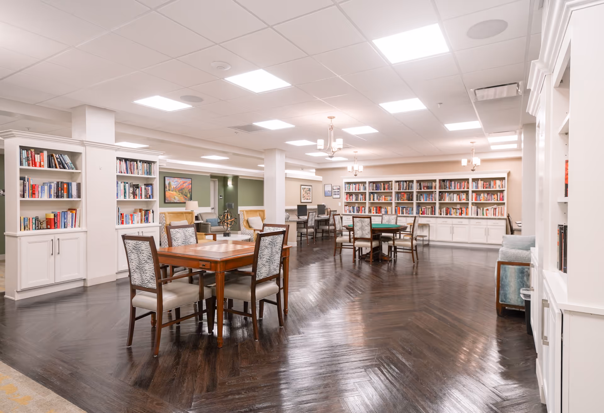 Open, well-lit communal library and lounge with bookshelves, tables, and chairs.