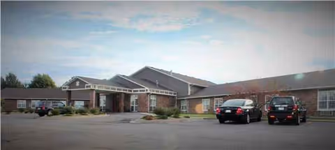 Exterior view of Aspire of Excelsior Springs facility with brick building and parked cars.