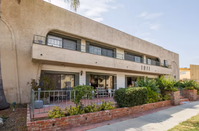 Two-story beige senior living facility exterior with front patio seating.