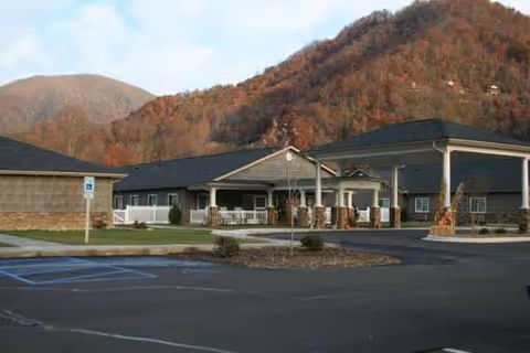 Exterior of Maggie Valley Nursing and Rehabilitation with a parking lot and mountain backdrop.