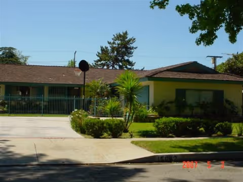 Exterior view of Angeles Assisted Living building with walkway, fence, and landscaping.