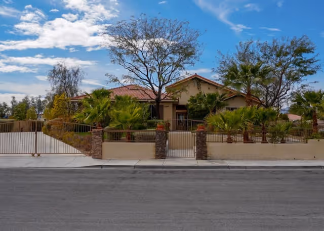 Exterior view of a Nevada Memory Care building with gated entrance and palm landscaping.