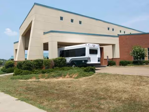 Exterior view of Madison County Nursing Home with a bus parked at the front entrance.