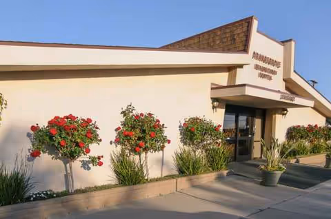 Exterior of Orangegrove Rehabilitation Hospital with red rose bushes along the entrance walkway.