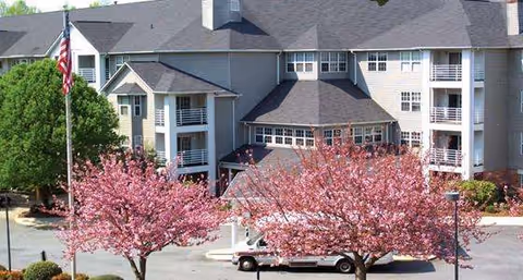 Front view of Valley View Retirement Community building with pink flowering trees and a parked van.