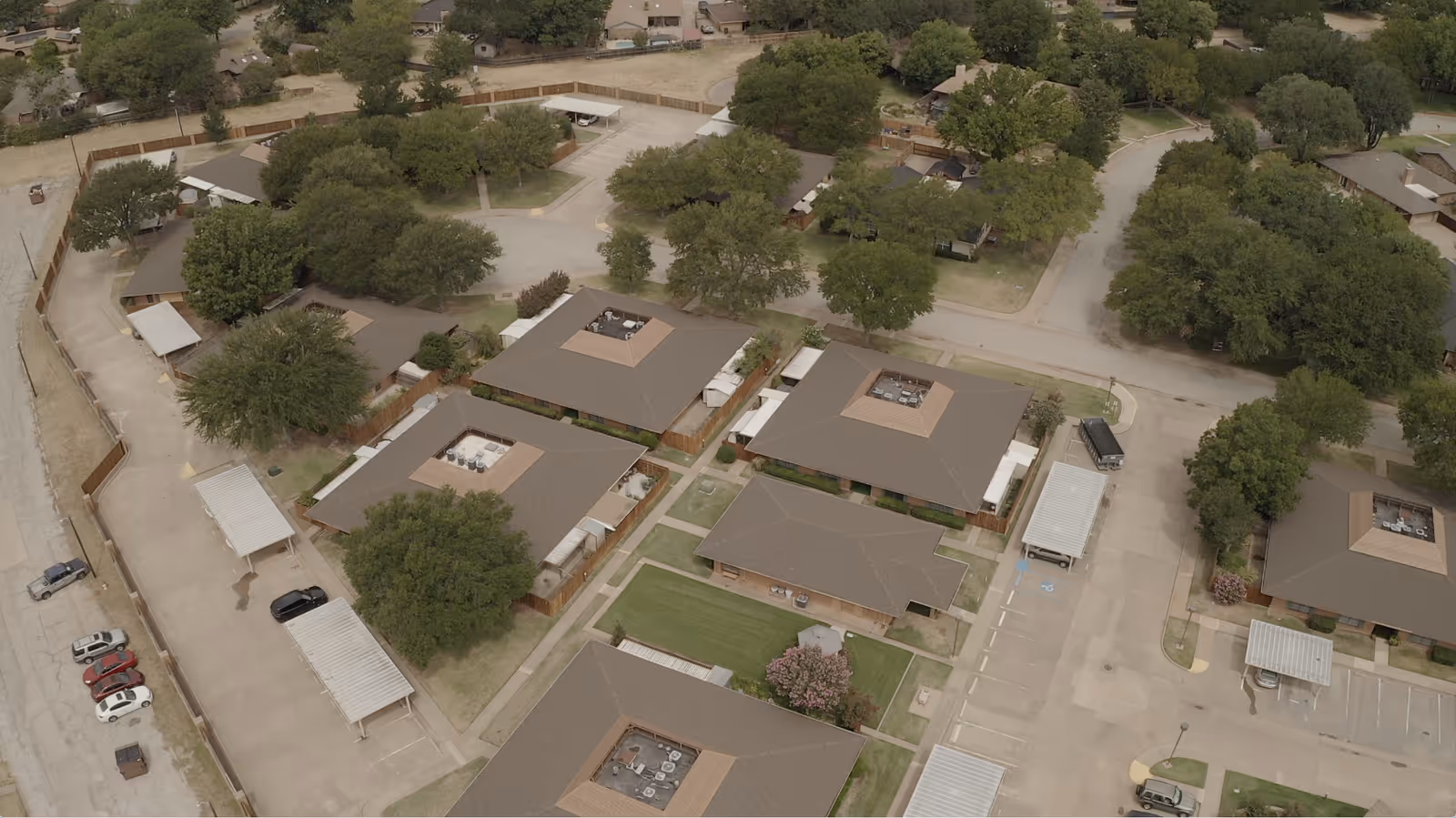 Aerial view of Presbyterian Manor showing multiple single-story buildings with brown roofs surrounded by trees, parking areas, and roads within a residential neighborhood.