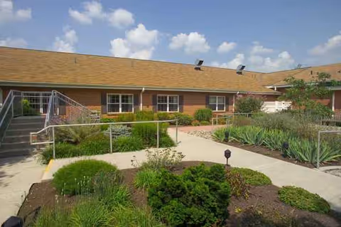 Front view of Hickory House Nursing Home with landscaping and a walkway.
