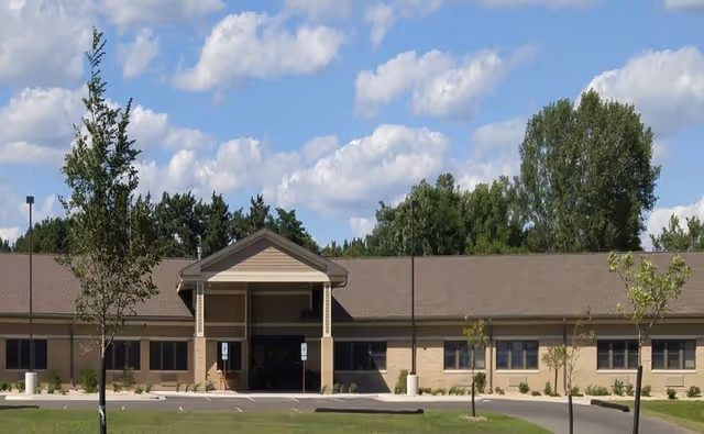 Single-story brick senior living facility with a covered entrance and front parking area.