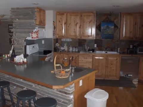 Rustic kitchen with wooden cabinets, a stone-accented island with bar stools, countertop appliances and a sink.