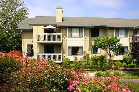 A two-story senior living building with balconies and manicured front landscaping.