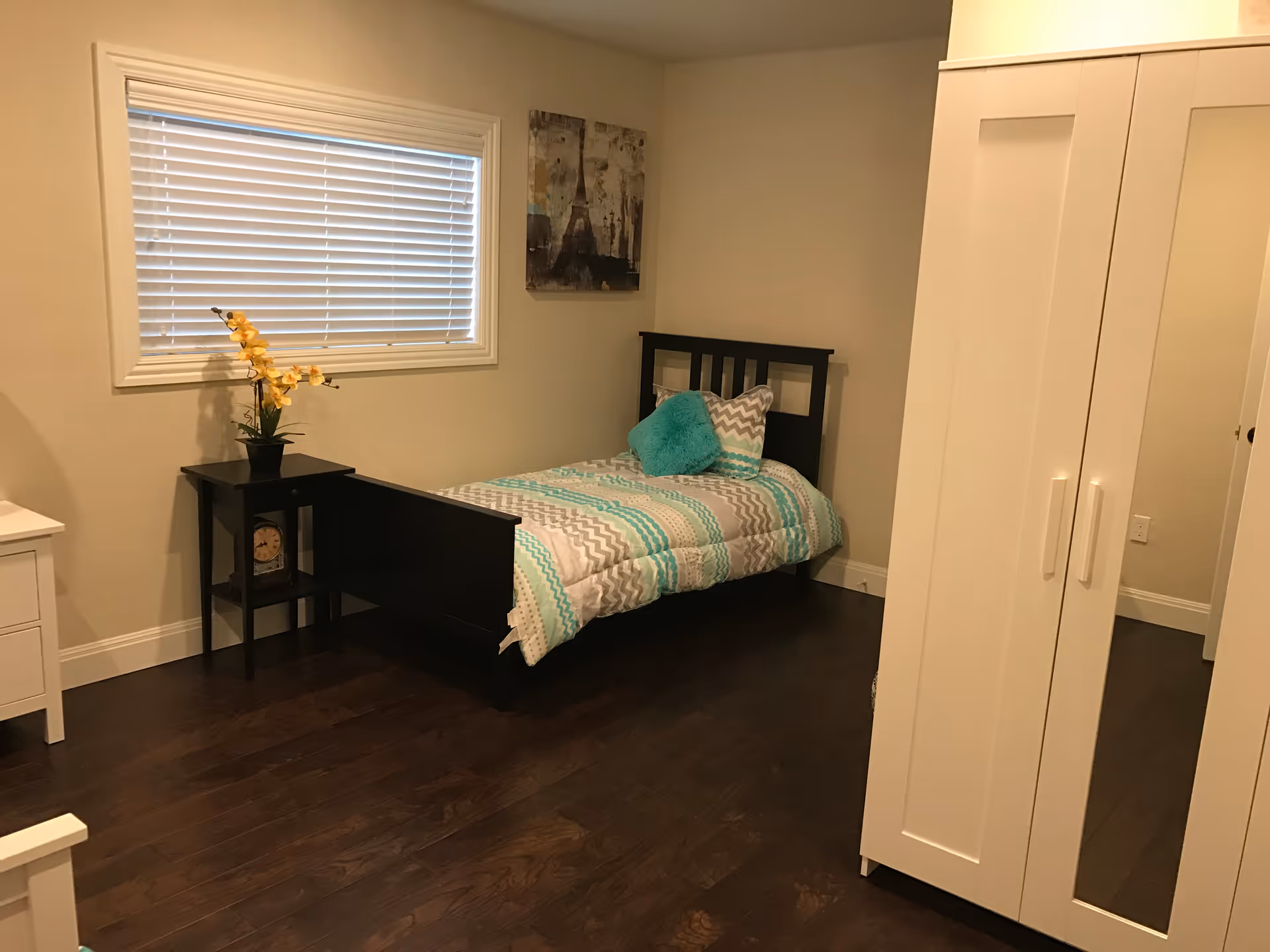 Small furnished bedroom with a single bed, nightstand, wardrobe and a window with blinds