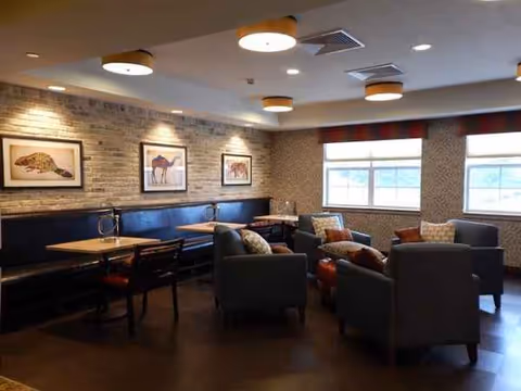 Cozy interior lounge with blue bench seating, armchairs, tables, and framed animal art.