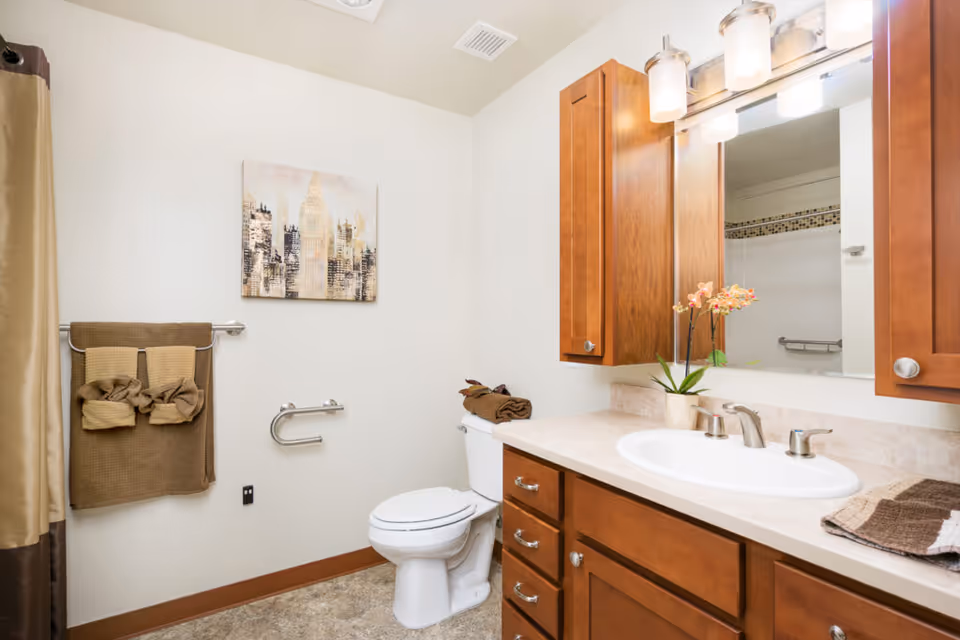 Bathroom with wooden vanity, sink and mirror, toilet, towel rack and shower curtain.
