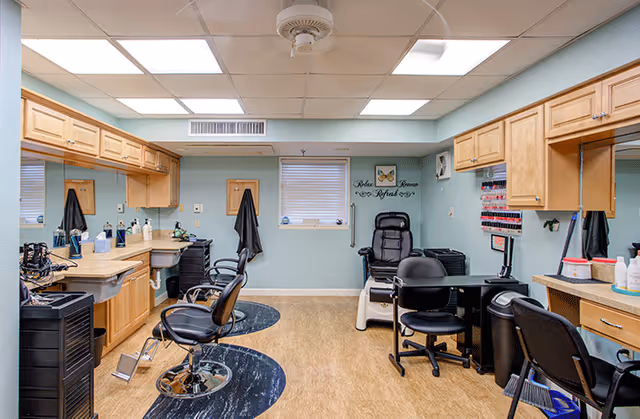 Interior salon-style room with barber chairs, a pedicure chair, manicure stations, cabinets, mirrors, and a nail polish rack.