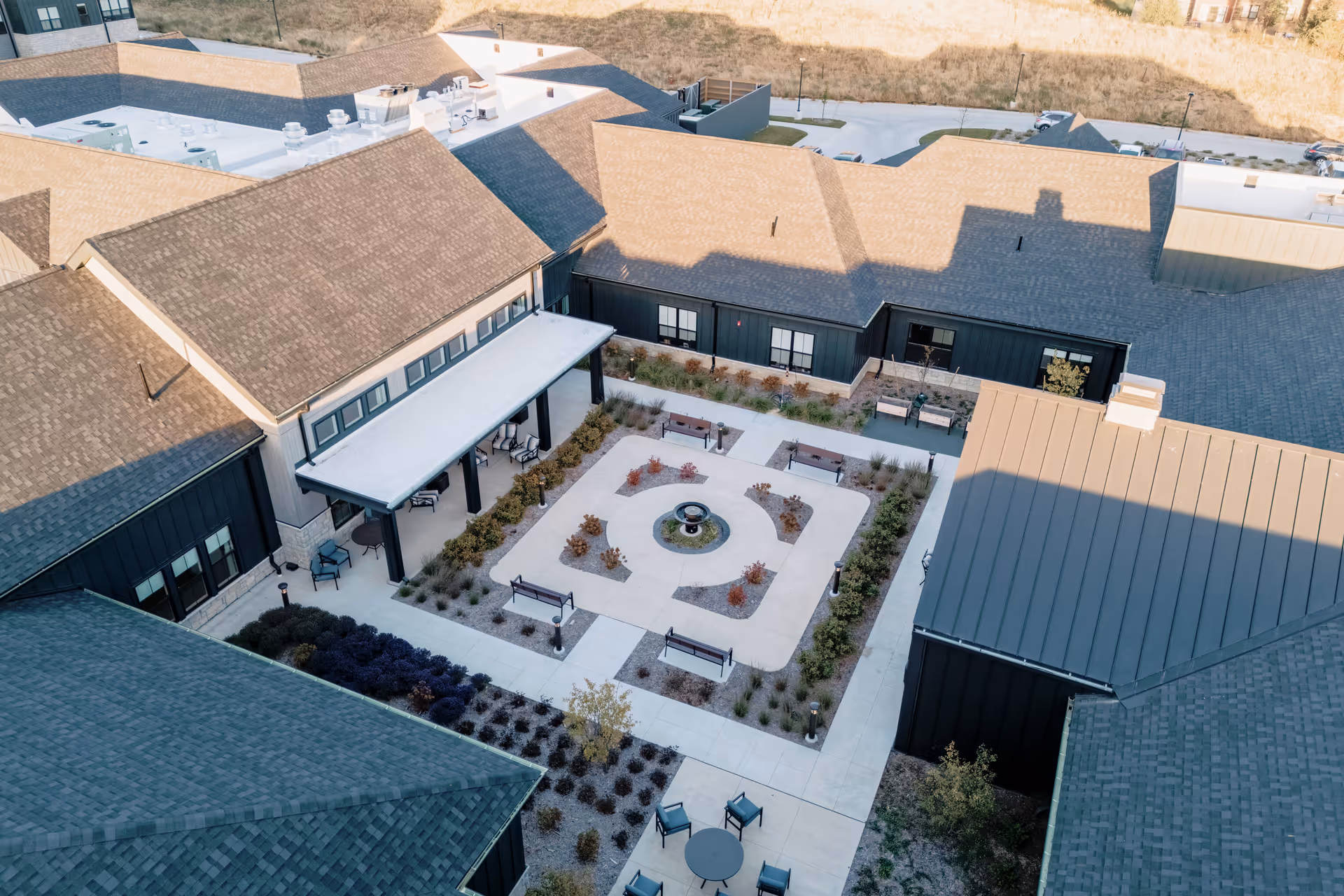 Aerial view of a landscaped central courtyard with a fountain, benches, and patio seating surrounded by the facility's buildings.