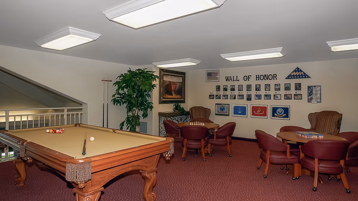 Recreation room with a pool table, card tables and chairs and a "Wall of Honor" display on the wall.