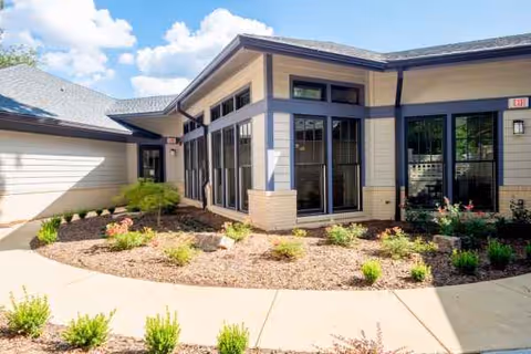 Modern single-story senior living facility exterior with large windows and landscaped entrance.
