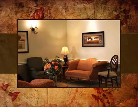Cozy lounge seating area with sofa, chairs, and lamps in a senior living facility.