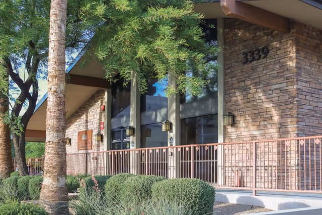 Exterior front entrance of a stone-clad building with address number 3339, lanterns, railing, and landscaping.