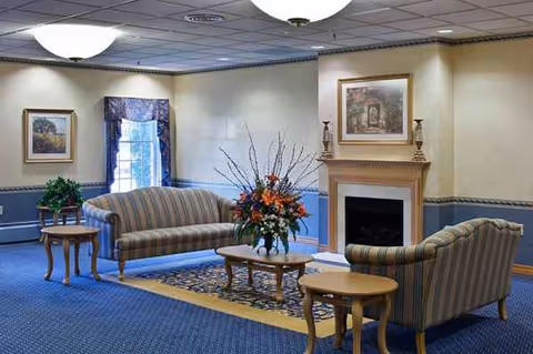 Cozy senior facility living room with striped sofas, a fireplace, and a floral centerpiece.