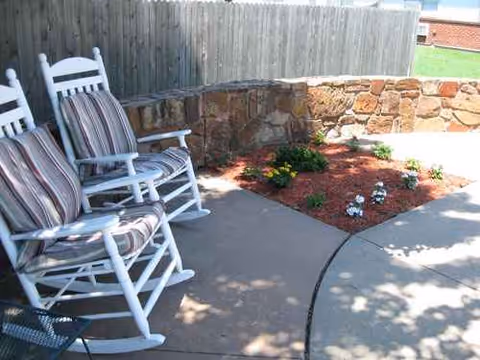 Outdoor patio at Medicalodges Dewey with white rocking chairs and a stone planter.