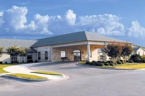 Exterior view of Woodway Rehabilitation & Healthcare Center entrance with curved drive and landscaping.
