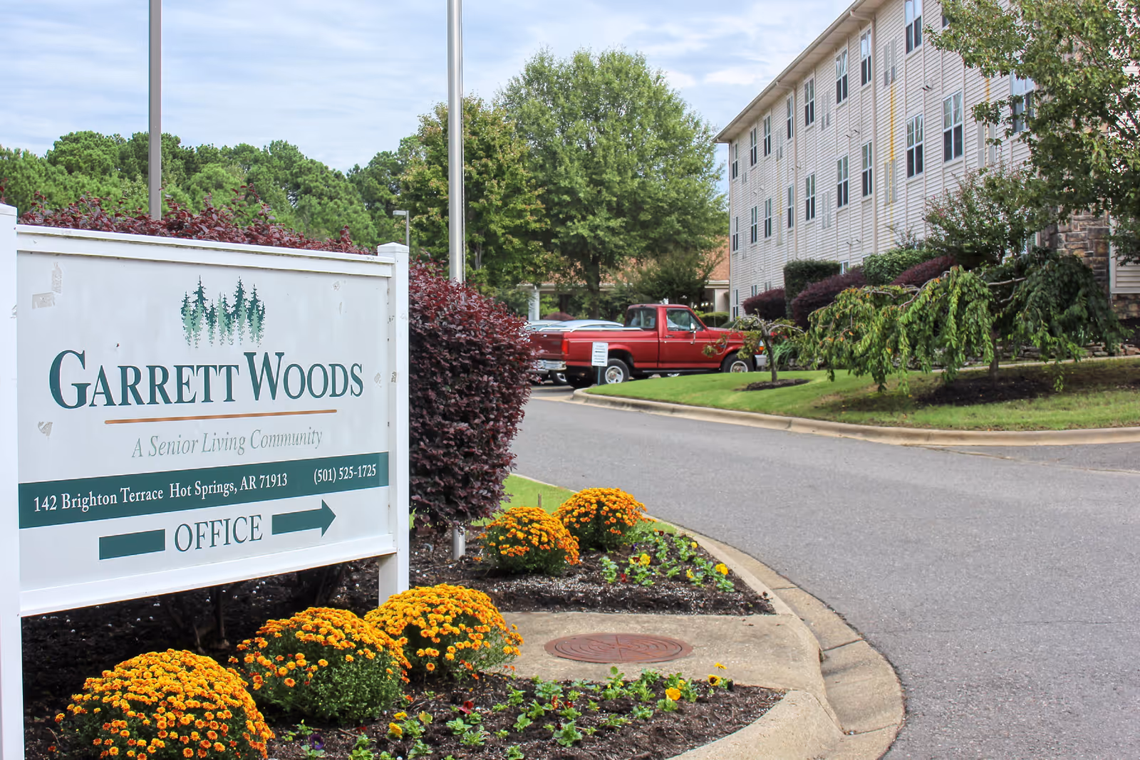 Exterior view of Garrett Woods Senior Living Community sign, building front, and landscaped entrance.
