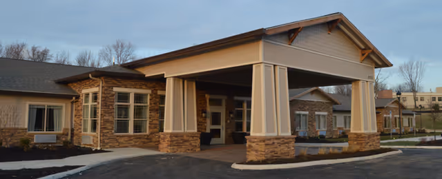 Covered front entrance with a porte-cochère and stone-clad columns on a single-story assisted living building.
