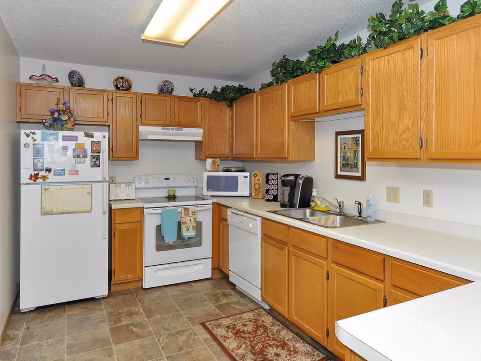 Bright kitchen with oak cabinets, white appliances (fridge, stove, microwave, dishwasher) and a long countertop with sink.