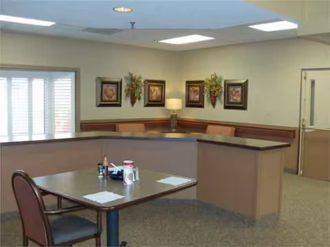 U-shaped reception counter with seating area, wall art, and a table in a quiet interior.