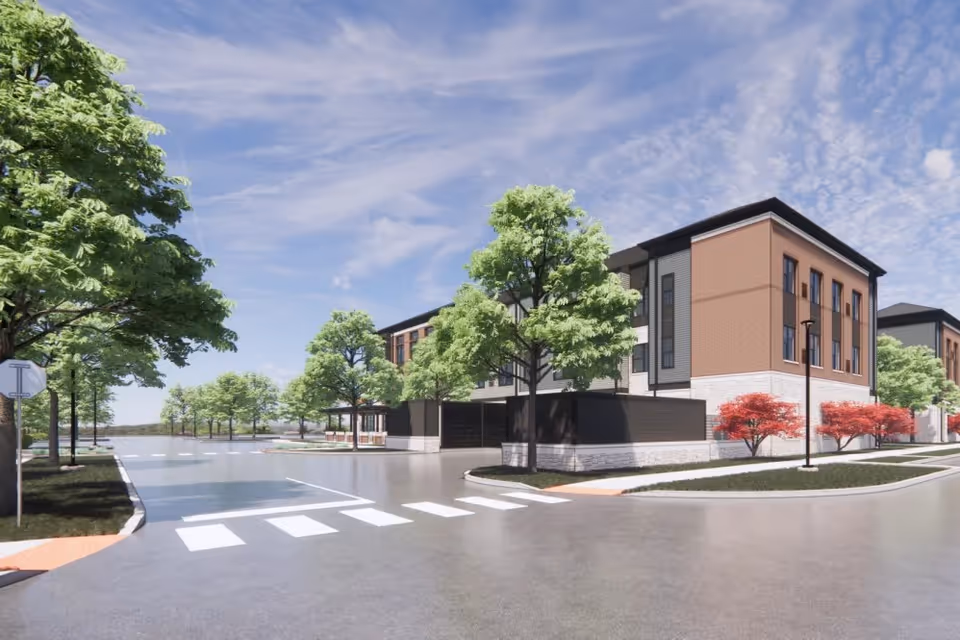 Exterior view of a modern senior living facility building with three stories, surrounded by trees and landscaping, under a partly cloudy sky.