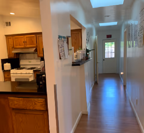 Long white hallway in a senior living facility with a kitchen on the left.