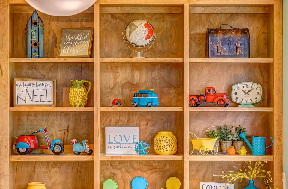 Wooden built-in shelves filled with colorful decorative items including toy vehicles, a globe, a clock, signs, and small plants.