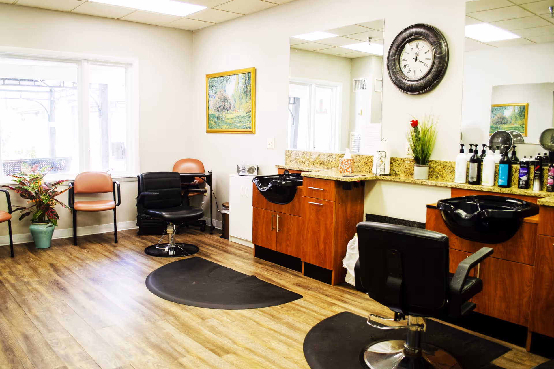 Bright interior salon area with styling chairs, wash sinks, mirrors, and waiting seats in an assisted living facility.