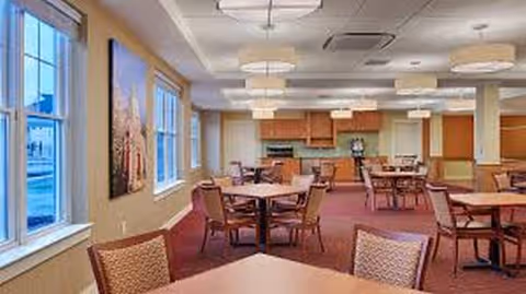 Bright dining room in a senior facility with round tables and chairs.