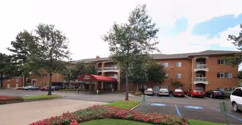 Exterior view of Holiday Chateau Ridgeland with brick building, red entrance awning, and parked cars.