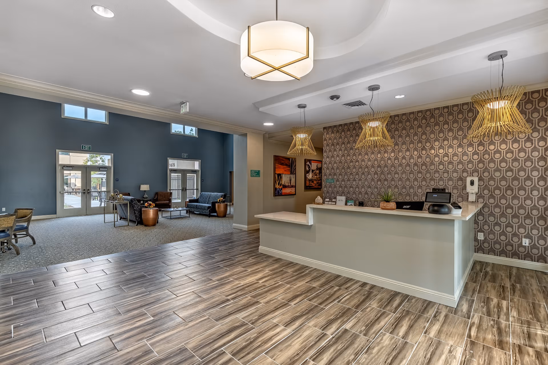 Lobby reception area with a front desk, pendant lights, and a seating area visible through a wide open space.