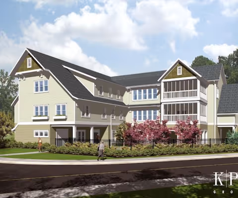 Exterior rendering of a three-story residential/senior living building with balconies, landscaping, and a sidewalk in front.