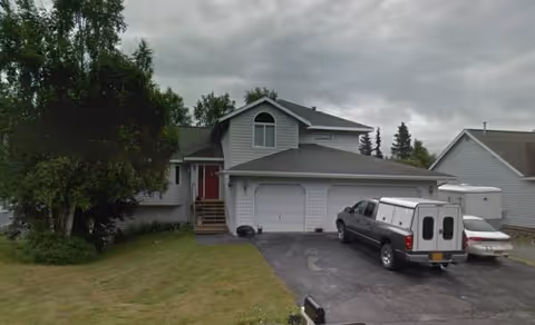 Front exterior of Nadon Family Home, a two-story grey house with a garage and parked vehicles.