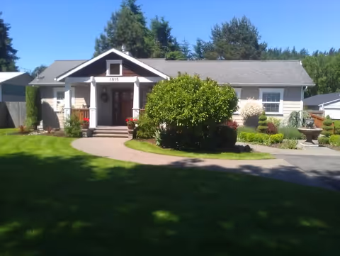 Single-story senior living facility with a manicured lawn, front entrance, and landscaped shrubs.