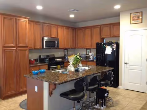 Marigold Home kitchen with granite island and wooden cabinets.