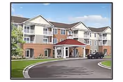 Exterior view of a multi-story senior living facility building with a covered entrance, a driveway, and a parked car. The building features a combination of brick and light-colored siding with balconies and windows. The sky is partly cloudy.