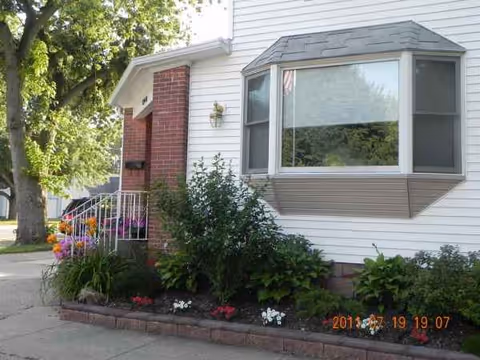 Front exterior of Petrona's Country Home with bay window and landscaped flower beds.